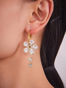 Detailed view of gold flower earrings with 5A cubic zirconia stones on a model