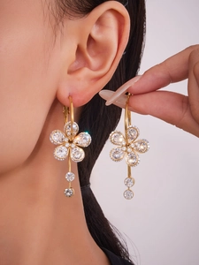 Macro shot of gold plated flower earrings with 5A zircon stones and dangled gems on ear