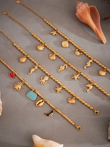 Macro detail of ocean-themed gold stainless steel charm bracelets with sea life pendants