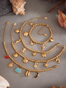 Detalle del conjunto de 4 piezas de acero inoxidable dorado con dijes marinos y caracolas