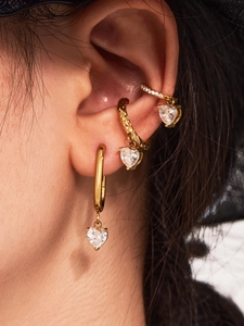 Detailed close-up of 18k gold plated hoop earrings and ear cuffs with heart zircon stones