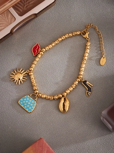 Detalle de pulsera de acero inoxidable dorado con colgantes náuticos y de moda