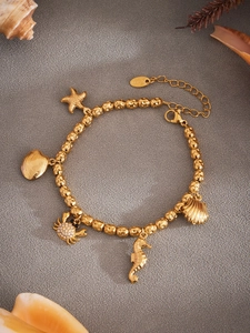 Detalle de pulsera de acero inoxidable dorado con colgantes marinos de pulpo y estrella