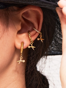 Detailed view of gold scissor earrings and pave zircon ear cuffs on a female model