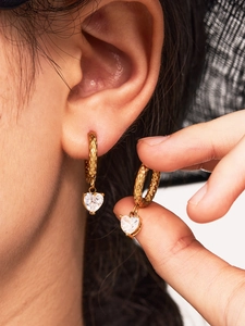 Close-up of heart-shaped zircon drop earrings with hammered texture 18k gold finish