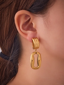 Macro detail of irregular double-loop hollow gold earrings worn by a model