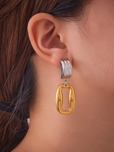 Detailed view of layered silver and 18k gold plated hollow oval earrings on model