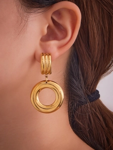 Close-up of chunky gold hoop earrings with ribbed texture on lobe and smooth hollow drop