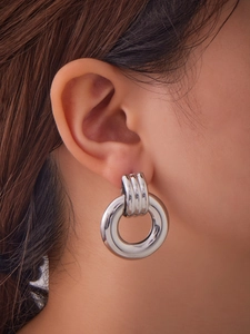 Close-up of irregular double-loop hollow earrings with 18k gold plating on model's ear