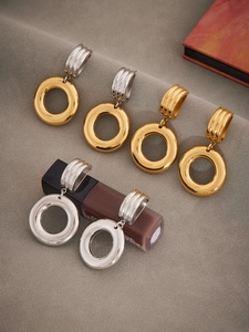 Detail of irregular hollow double hoop earrings in high-polish gold and silver finish