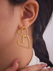 Close-up of dual interlocking heart drop earrings in polished 18k gold on model