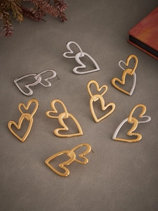 Detail of overlapping heart earrings in gold and silver finishes on a textured surface
