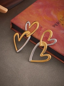 Macro detail of interlocking double heart earrings in mixed gold and silver polished finish