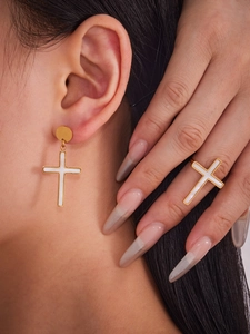 Primo piano del set con anello e orecchini a croce in acciaio dorato indossato da una donna