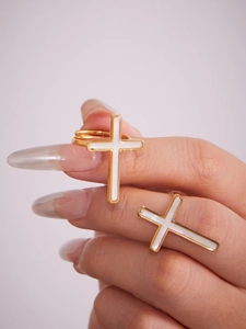 Primo piano della mano con anelli a croce placcati oro 18k con inserti in conchiglia