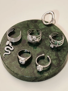 Detailweergave van zilveren ringen en oorbellen met groene zirkoon en palmboom