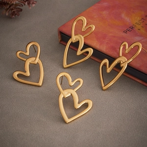 18k gold plated stainless steel double heart drop earrings on a grey textured surface