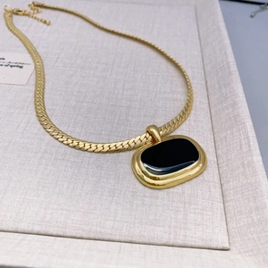 Minimalist gold necklace with a black enamel rectangular pendant and flat curb chain