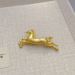 Luxurious gold horse brooch with sparkling zircons on a soft textured background