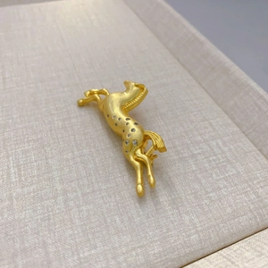 Elegant gold-plated galloping horse brooch with sparkling zircons on a beige tray