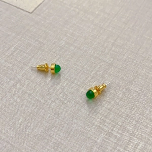 Detailansicht der goldenen Ohrstecker mit grünen Achatsteinen und Silberstiften auf Tuch