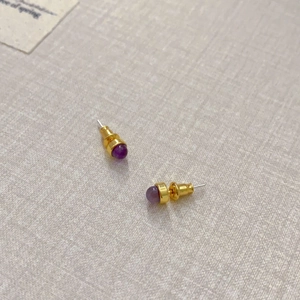 Detailansicht der eleganten lila Perlenohrstecker mit poliertem goldfarbenem Metall