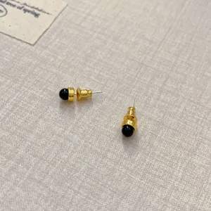 Detailansicht minimalistischer goldener Ohrstecker mit runden schwarzen Onyx-Einlagen