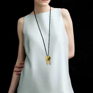 Collier élégant à double clé dorée avec cordon noir sur un haut en soie grise
