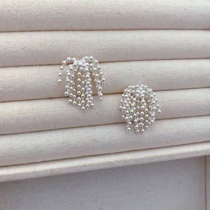 Elegant silver fringe tassel drop earrings with beaded cluster design on beige display