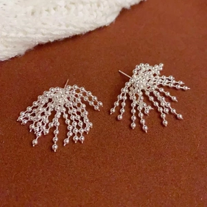 Detailed close-up of silver-tone beaded fan-shaped earrings on a plush velvet background