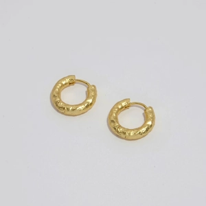 Detail of gold-plated hoop earrings featuring a handcrafted hammered texture finish