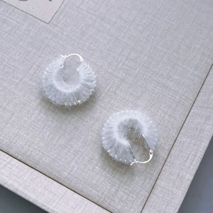 Detail of white fluffy hoop earrings featuring soft faux fur texture and silver hooks