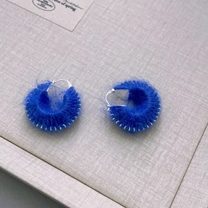 Macro shot of fluffy royal blue hand-woven wool hoop earrings with silver plated ear hooks