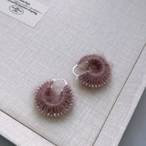 C-shaped hoop earrings with purple wool knit finish on textured gift box background
