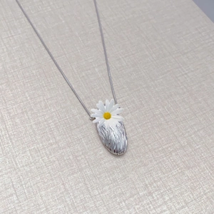Minimalist silver oval pendant with brushed texture and small white daisy on snake chain