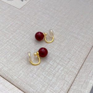 Detail of red bead ear clips with gold metal and clear silicone pads for comfort