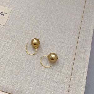 Detailed close-up of 12mm golden faux pearl earrings with elegant curved metal ear hooks
