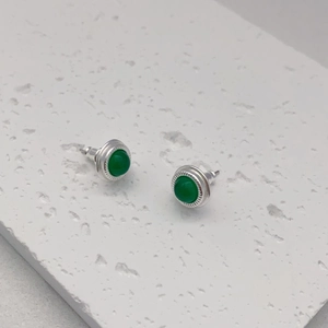 Macro detail of round green agate studs with textured silver plating and gear edges