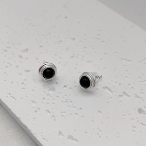 Macro shot of silver stud earrings with black onyx stone inlay and textured border