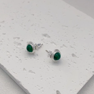 Macro shot of silver studs with round green malachite inlay on textured stone