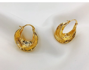 Detail of 18K gold plated earrings with irregular lava texture on white silk background