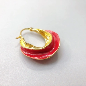 Detail of red enamel earrings with golden hammered texture and irregular wave design