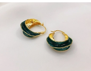 Detail shot showing the hammered gold texture and green enamel on wavy earrings