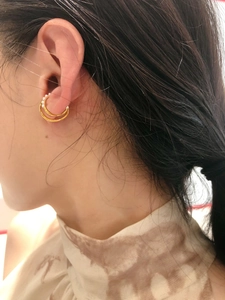 Nahaufnahme einer zweilagigen goldenen Ohrmanschette mit kleinen Perlen am Ohr
