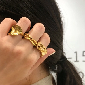 Close-up of three-piece gold plated ring set featuring wavy, Cuban chain, and textured designs