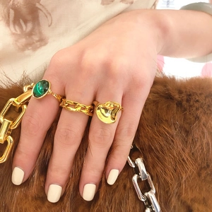 Close-up of three-piece 18K gold plated ring set with green gem and Cuban chain