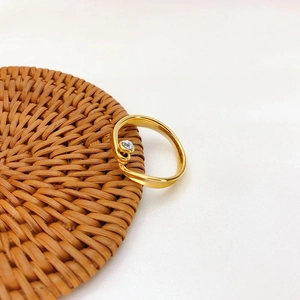 Detailansicht des vergoldeten Wickelrings mit Zirkonia-Stein auf einer geflochtenen Matte