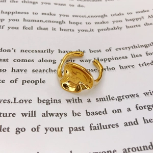 Detail of a gold adjustable ring with irregular lava texture on a white book page