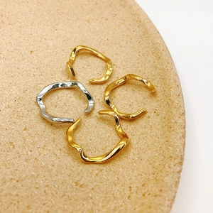 Detailansicht von vier unregelmäßig welligen Ringen in Gold und Silber auf Steintablett