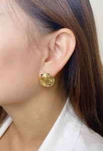 Détail du clou d'oreille coquillage plaqué or 18 carats avec gemmes sur une oreille